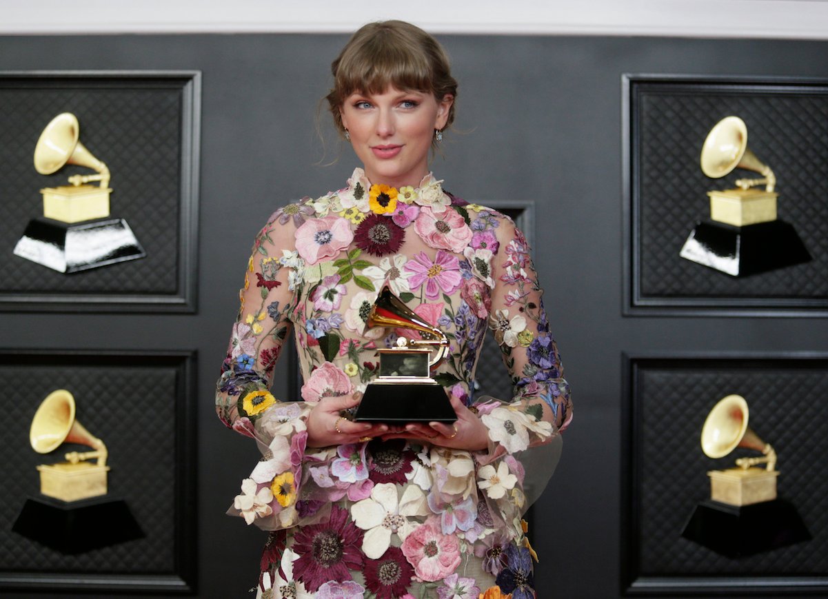 Taylor Swift holding a Grammy Award at the 2021 ceremony in a floral dress