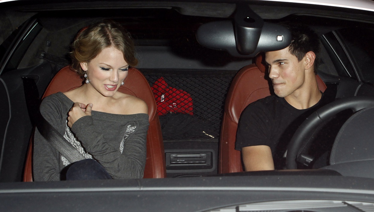 Taylor Swift and Taylor Lautner smile flirtatiously at one another while in a car