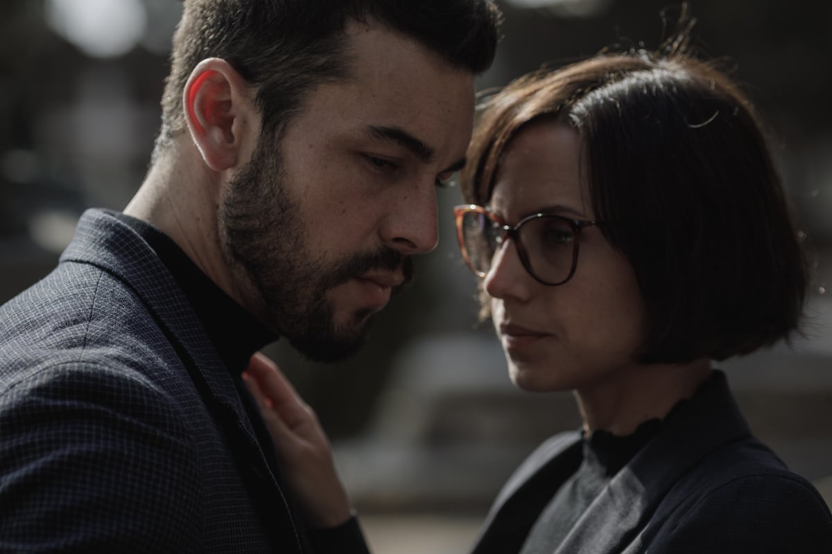 Woman with short hair and glasses touching a man's chest in The Innocent