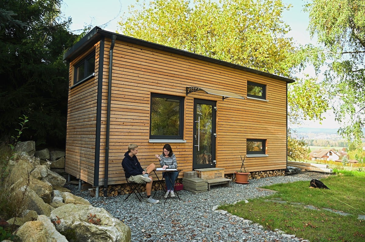 A couple sits outside a tiny house village in Germany