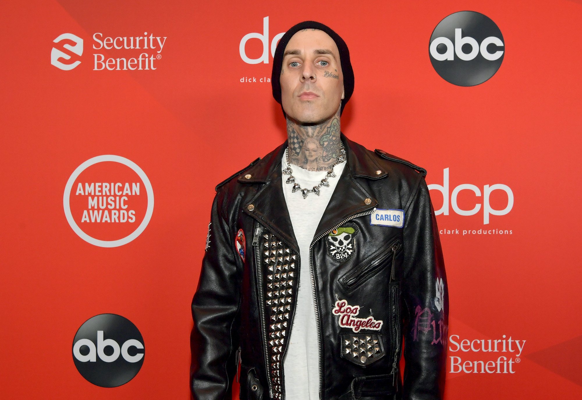 Travis Barker in front of a red background
