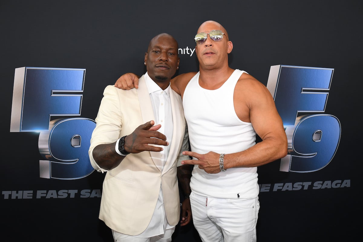 Tyrese Gibson and Vin Diesel stand next to each other on the red carpet dressed in all white