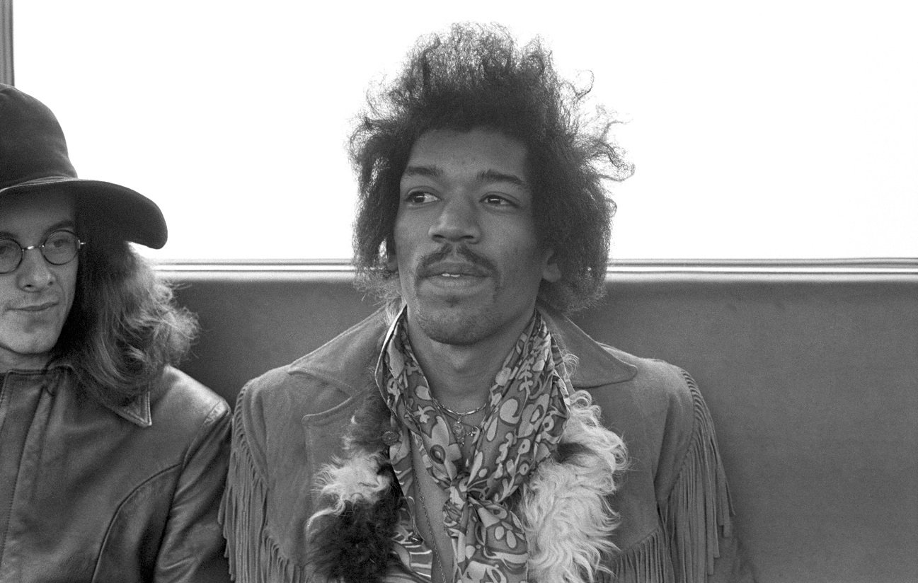 Jimi Hendrix smiles and looks off-camera with Noel Redding to his right