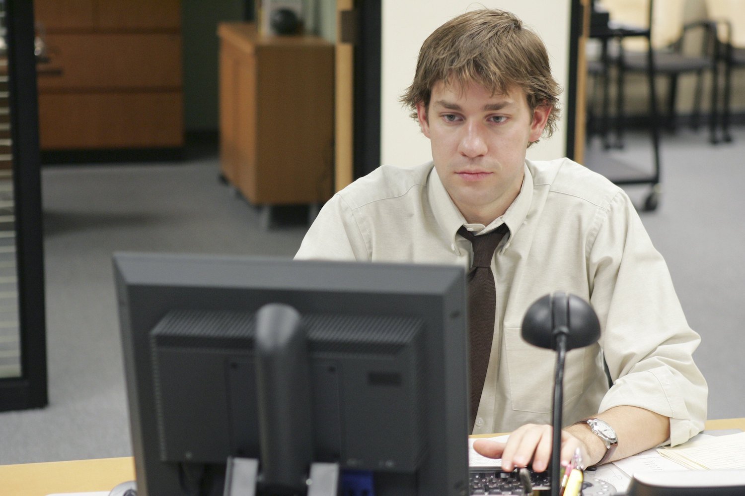'The Office' star John Krasinski sits at a desk as Jim Halpert