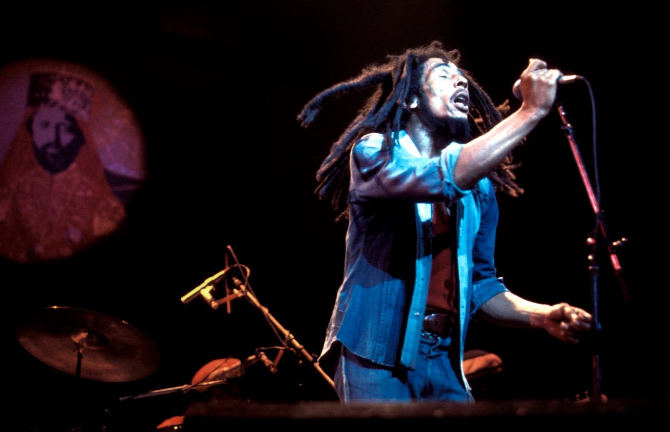Bob Marley holds the microphone with his eyes closed on stage in the late 1970s