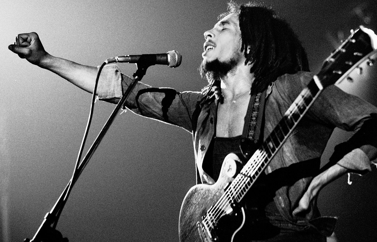 Bob Marley, eyes closed, holds his fist out to the crowd during a 1976 performance