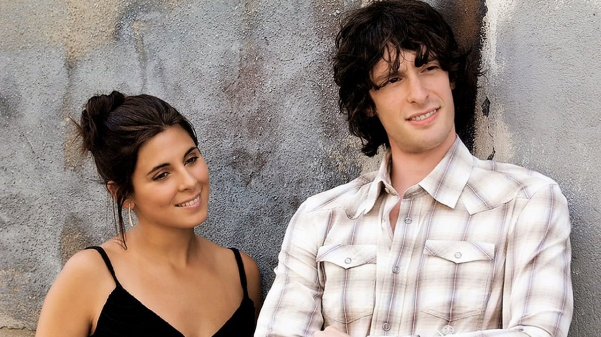 Jamie Lynn Sigler as Meadow Soprano and Will Janowitz as Finn DeTrolio smile with their backs to a wall