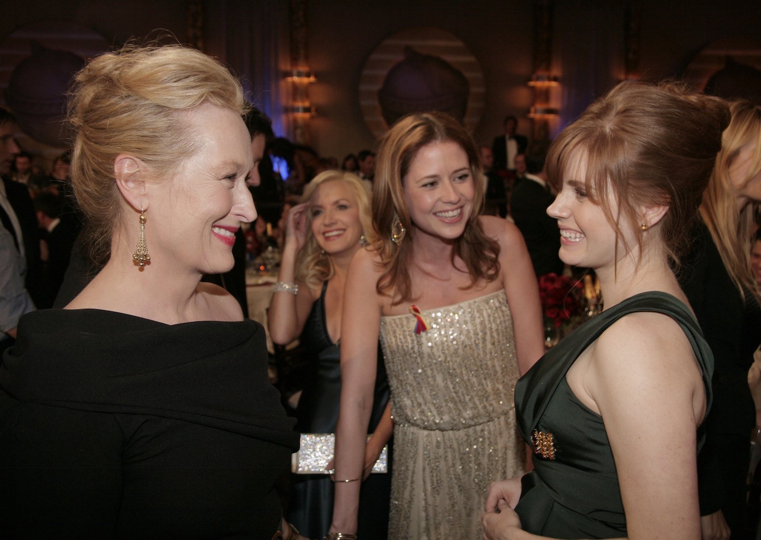Meryl Streep talks to Amy Adams as Jenna Fischer approaches, laughing, at the Golden Globes in 2010