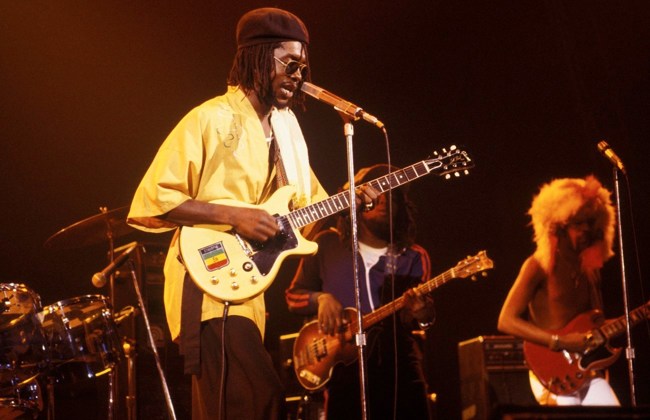 Peter Tosh plays guitar and sings on stage with his bandmates behind him