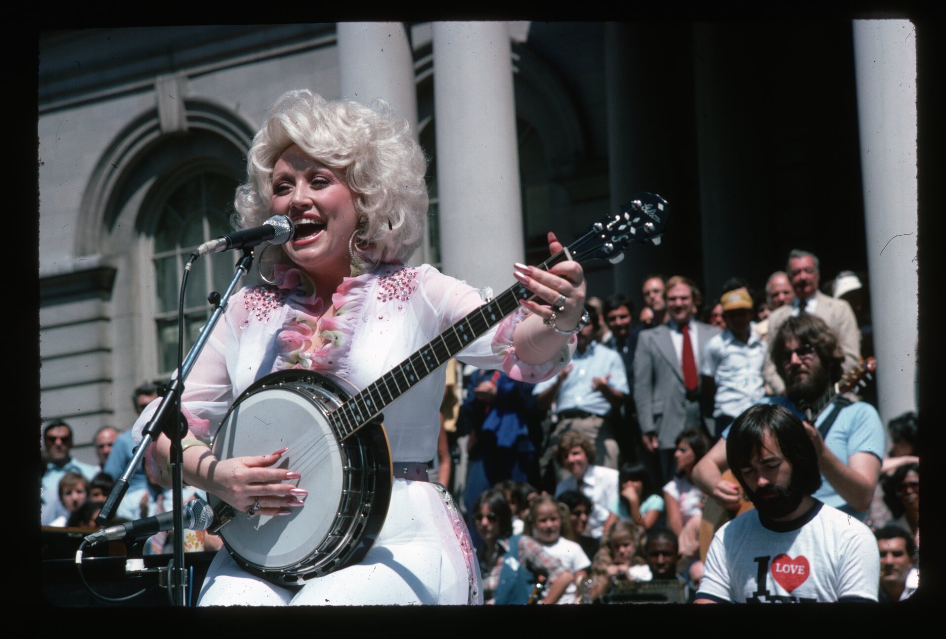 Dolly Parton playing banjo and singing for a live audience.