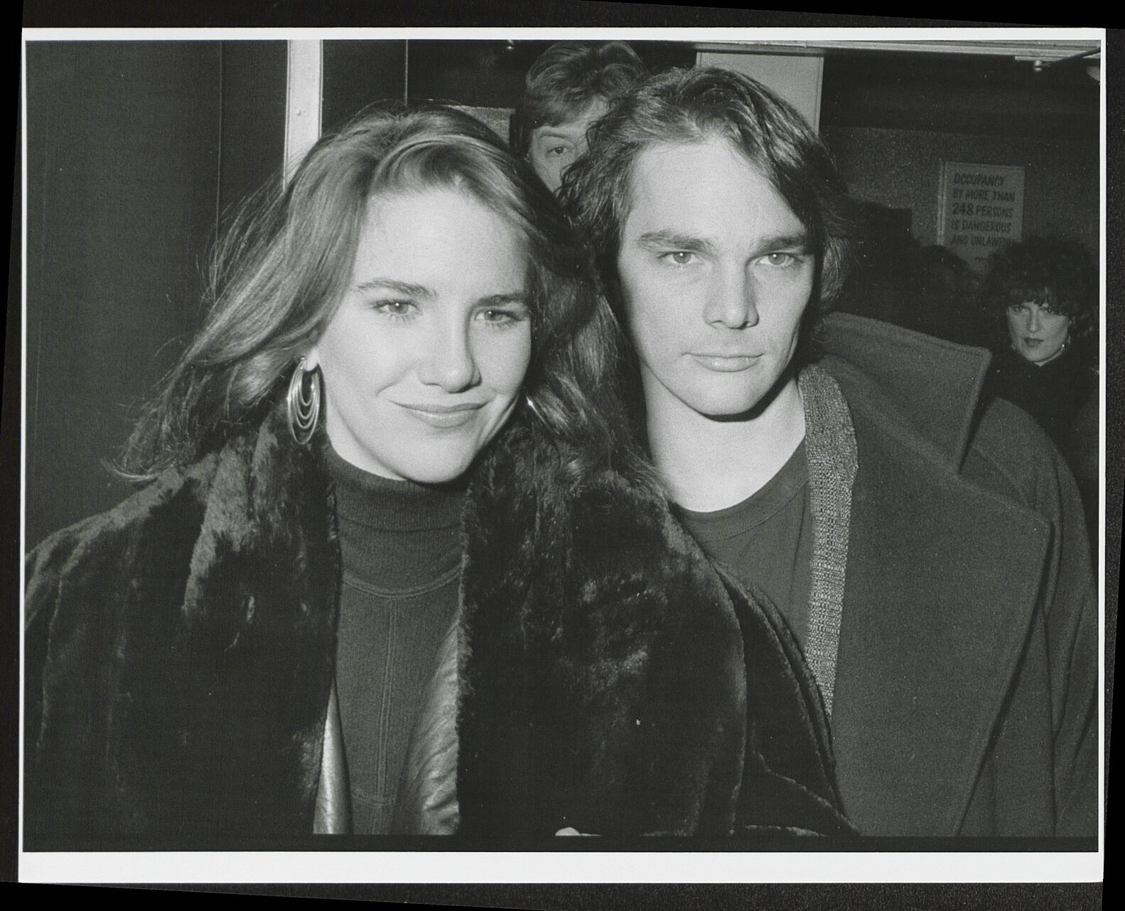 Melissa Gilbert and Bo Brinkman in black and white. Brinkman is in a fur coat and Brinkman is standing closely behind her.