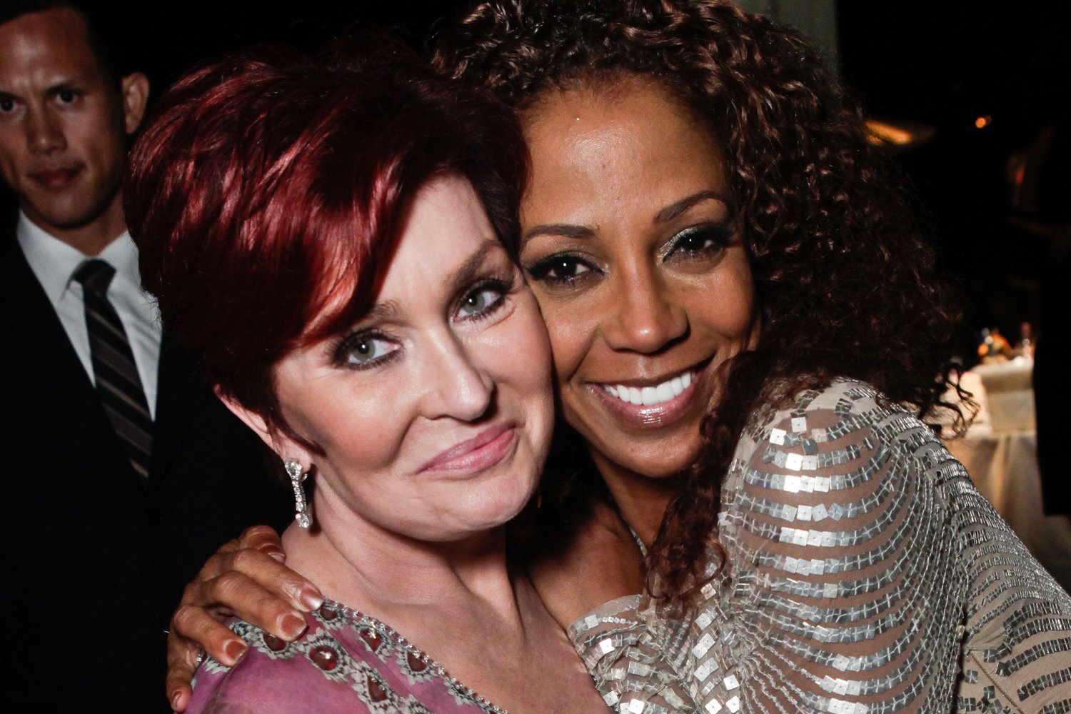 Sharon Osbourne and Holly Robinson Peete embracing each other and smiling for the camera