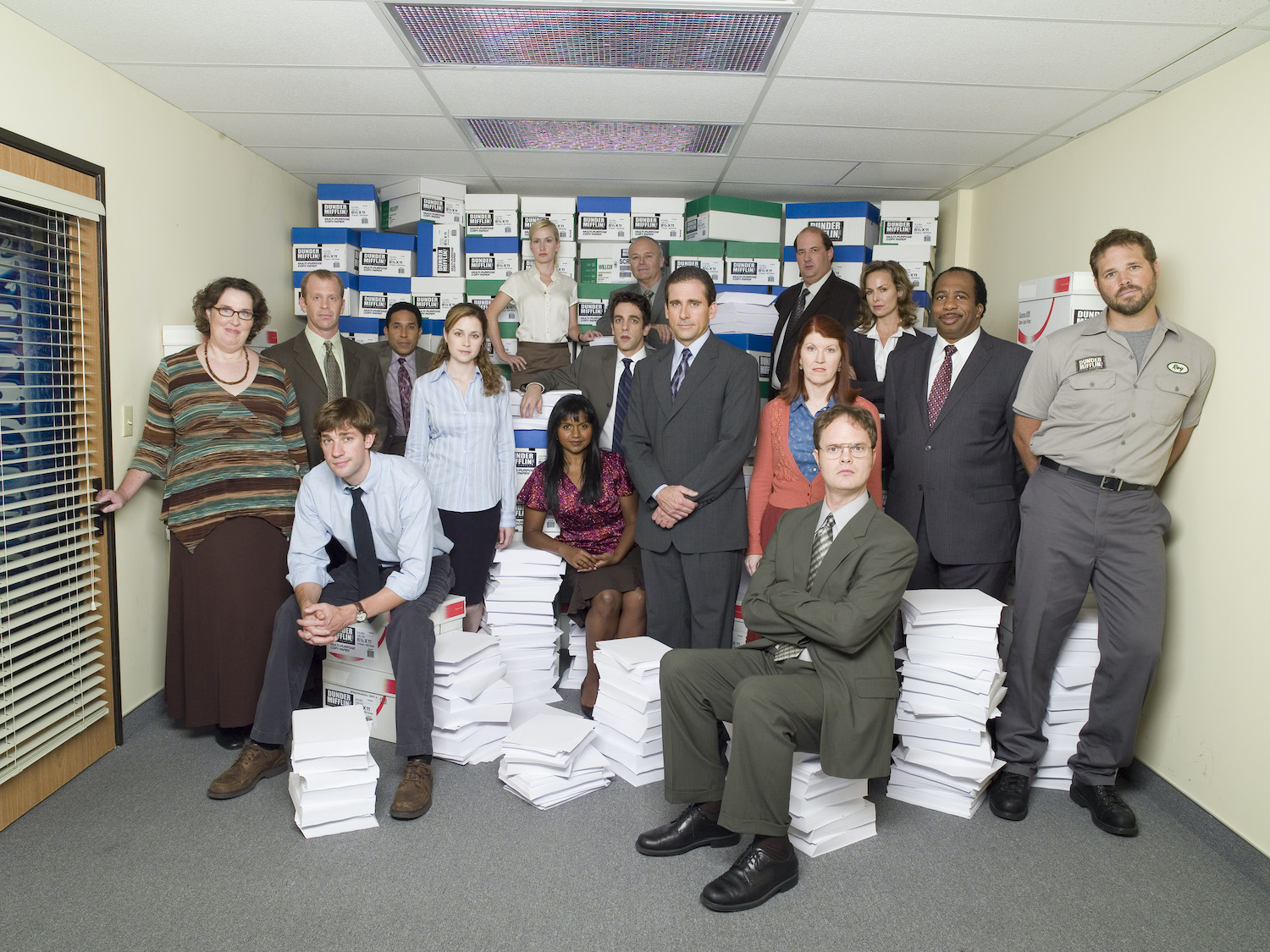 'The Office' cast poses in character amid piles of paper.