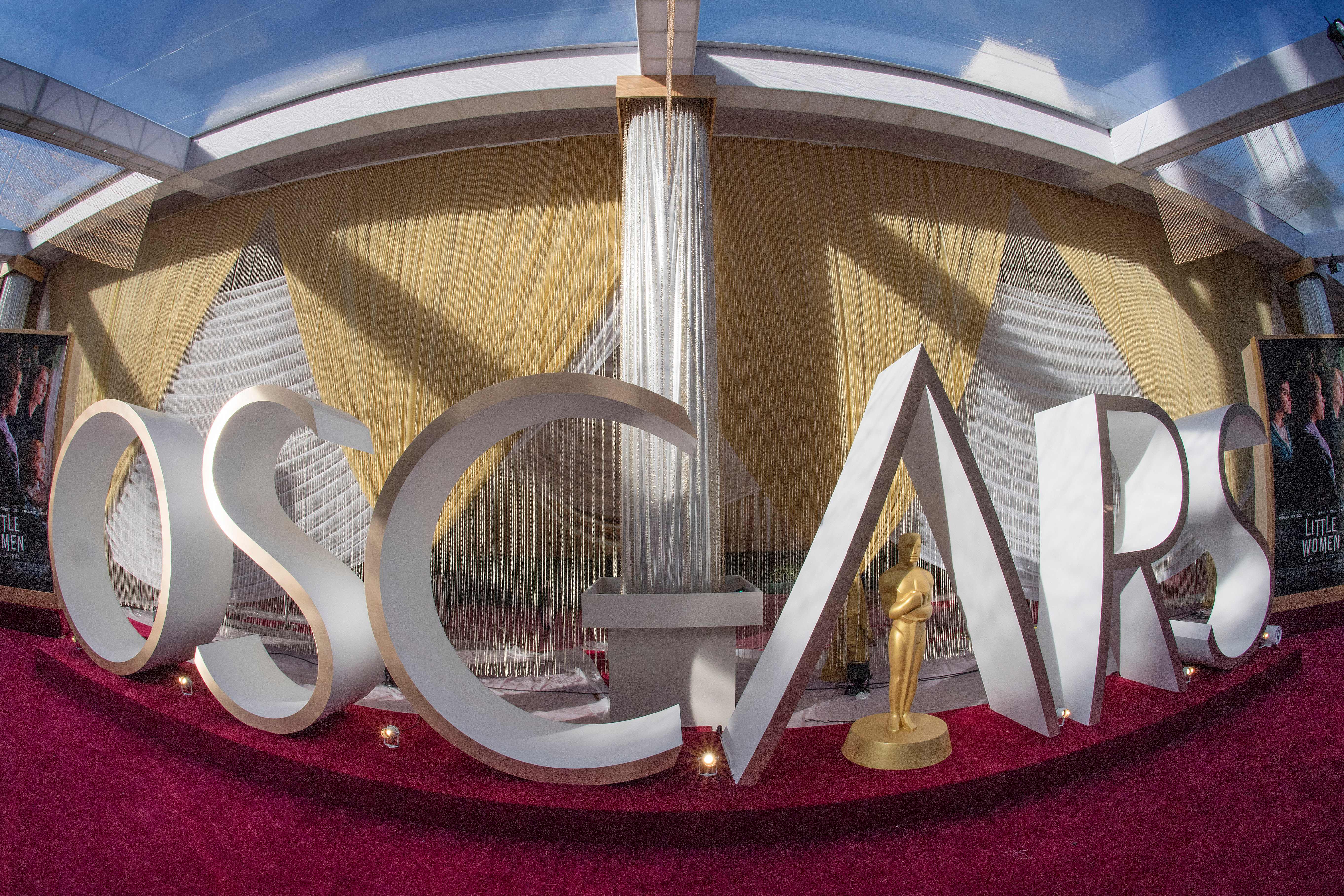 An Oscars sign and statue are displayed on the red carpet area