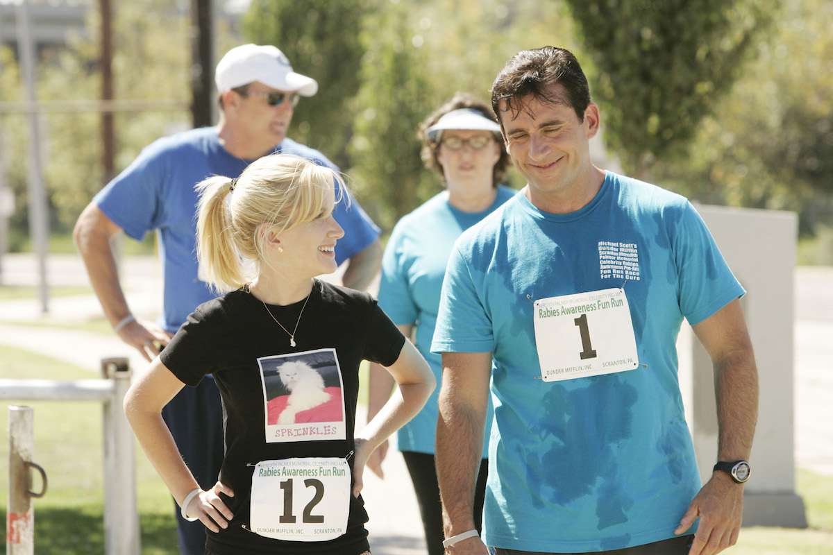 Angela Kinsey as Angela Martin and Steve Carell as Michael Scott are dressed in running clothes and stop to talk on the street in 'The Office'