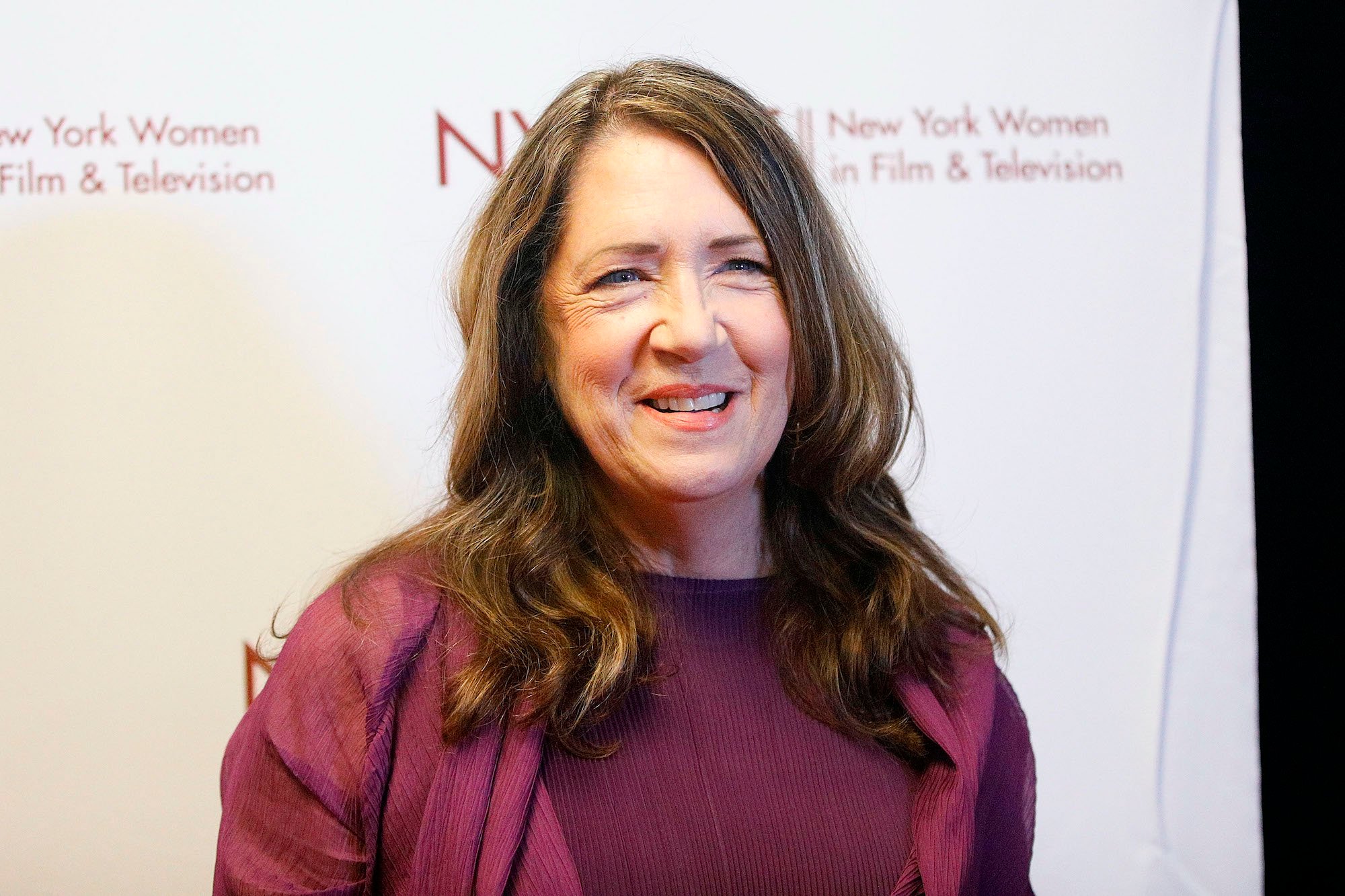 Ann Dowd smiling in front of a white background