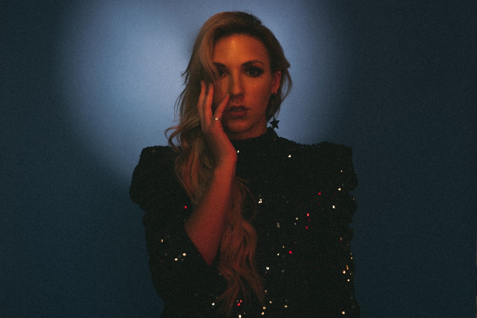 Singer Bailey Coats in a sequin dress against a dark background