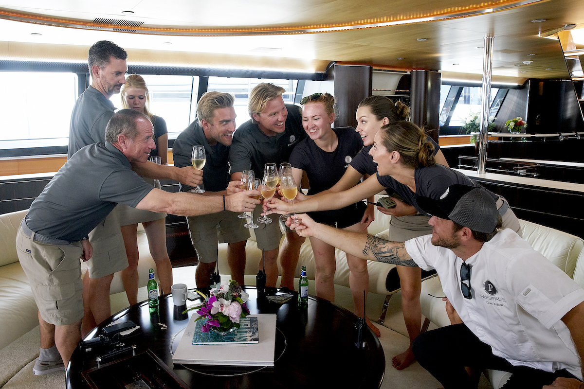 Below Deck Sailing Yacht Season 1 crew toast to a successful charter. Captain Glenn Shephard, Byron Hissey, Madison Stalker, Parker McCown, Paget Berry, Ciara Duggan, Georgia Grobler, Jenna MacGillivray, Adam Glick