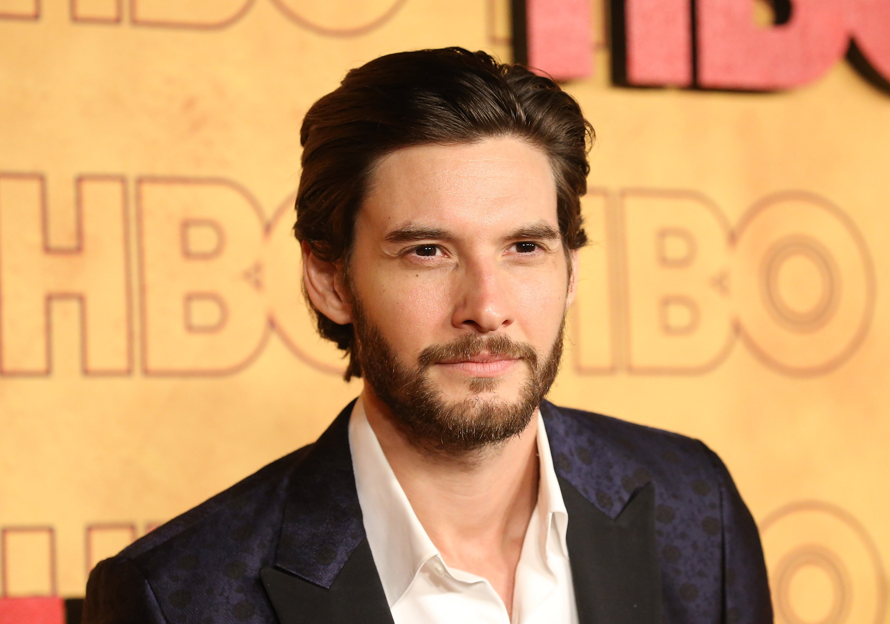 Actor Ben Barnes stands in front of a gold background with the HBO logo