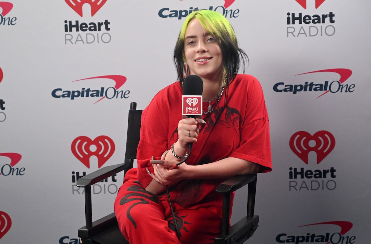 Billie Eilish speaks backstage in a red outfit during the 2021 iHeartRadio ALTer EGO stream