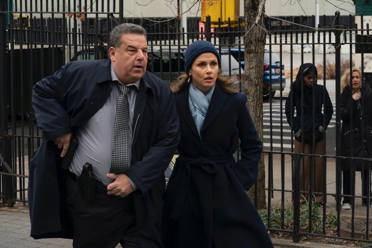 Steven Schirripa as Det. Anthony Abetemarco and Bridget Moynahan as Erin Reagan stand next to each other in a park in winter coats on 'Blue Bloods'