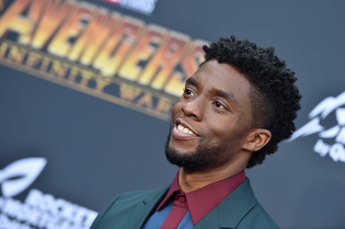 Chadwick Boseman smiles in a suit with a red shirt and black jacket at the 'Avengers: Infinity War' premiere
