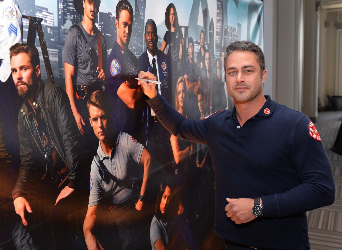 Taylor Kinney signs a poster as he attends a press junket for NBC's 'Chicago Fire', 'Chicago P.D.' and 'Chicago Med' at Cinespace Chicago Film Studios on November 9, 2015