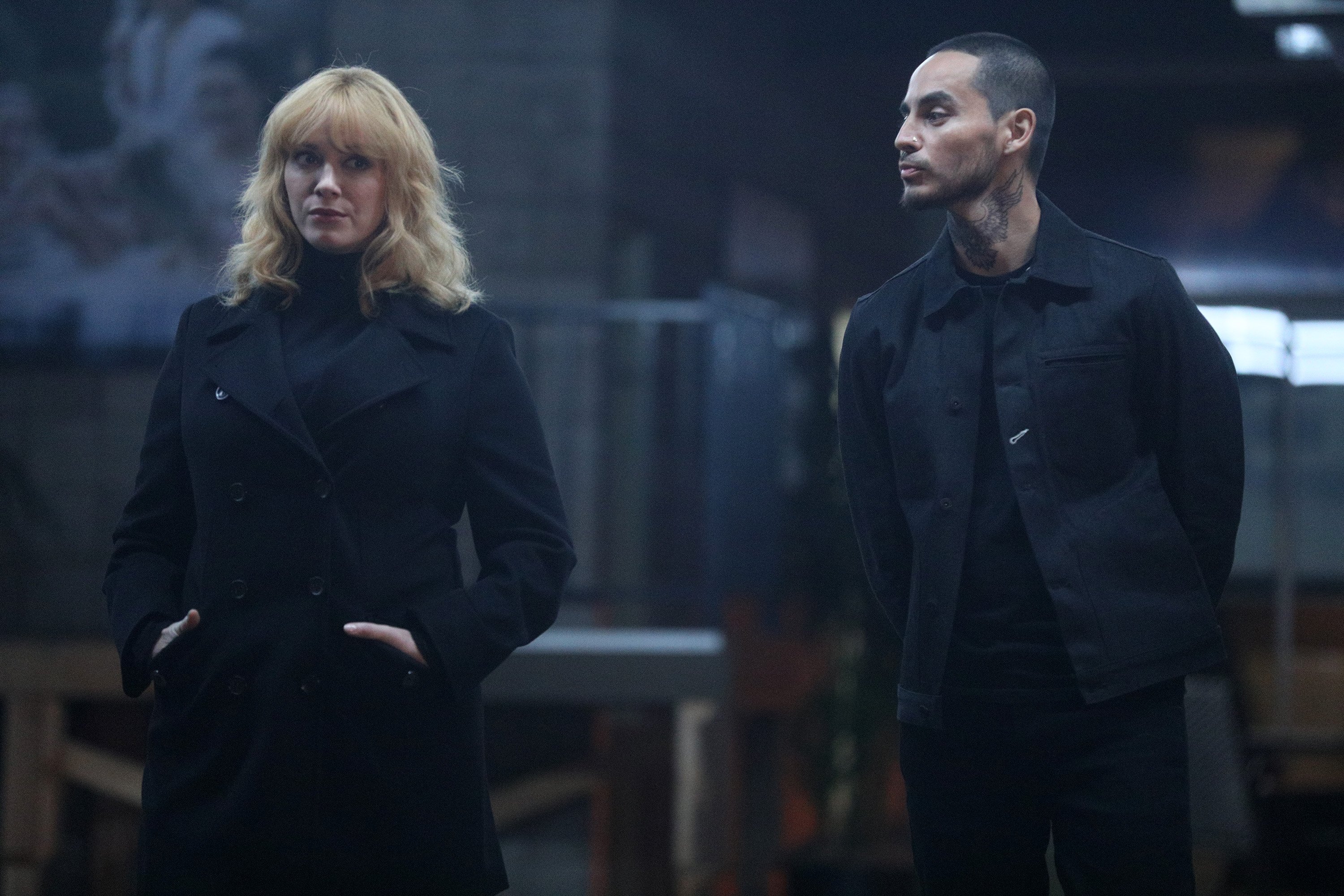 Good Girls stars Christina Hendricks and Manny Montana as Beth and Rio wearing all-black during a scene.