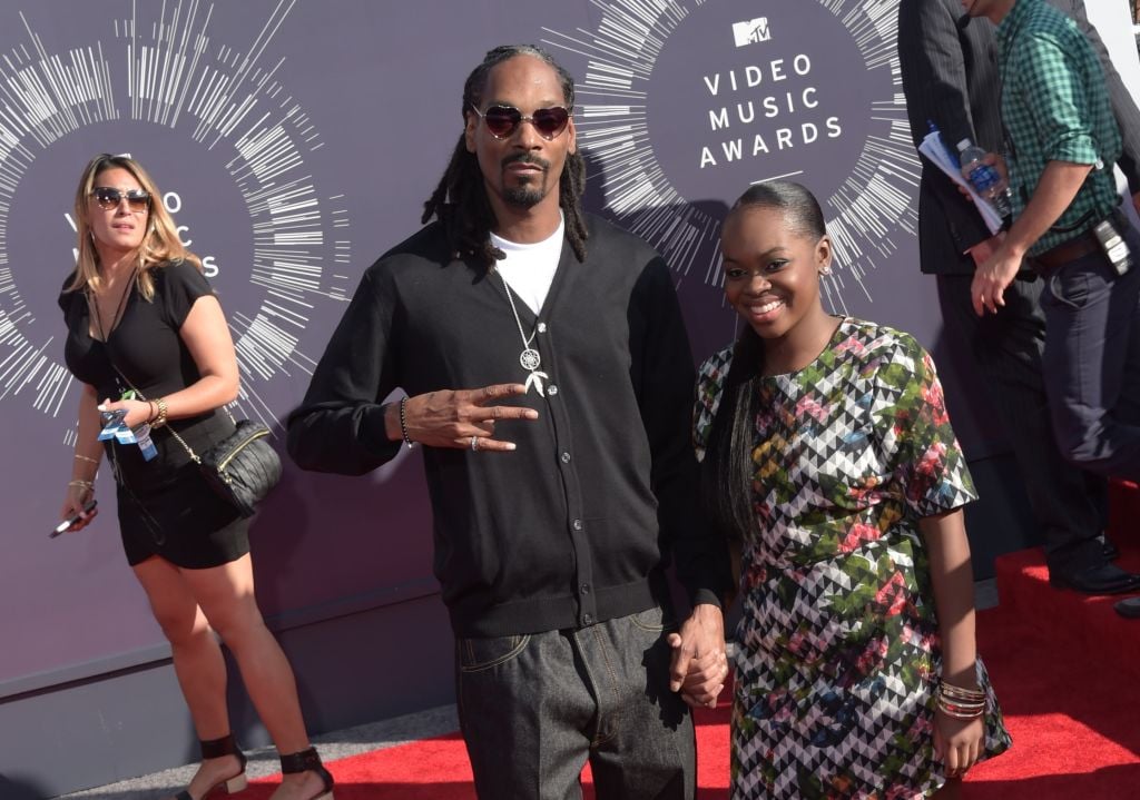 Rapper Snoop Dogg, dressed in a black zip-up, white t-shirt, and grey slacks, arrives with his arm around his daughter Cori Broadus, who's wearing a zig-zag, multi-colored dress on the red carpet for the 31st MTV Video Music Awards 
