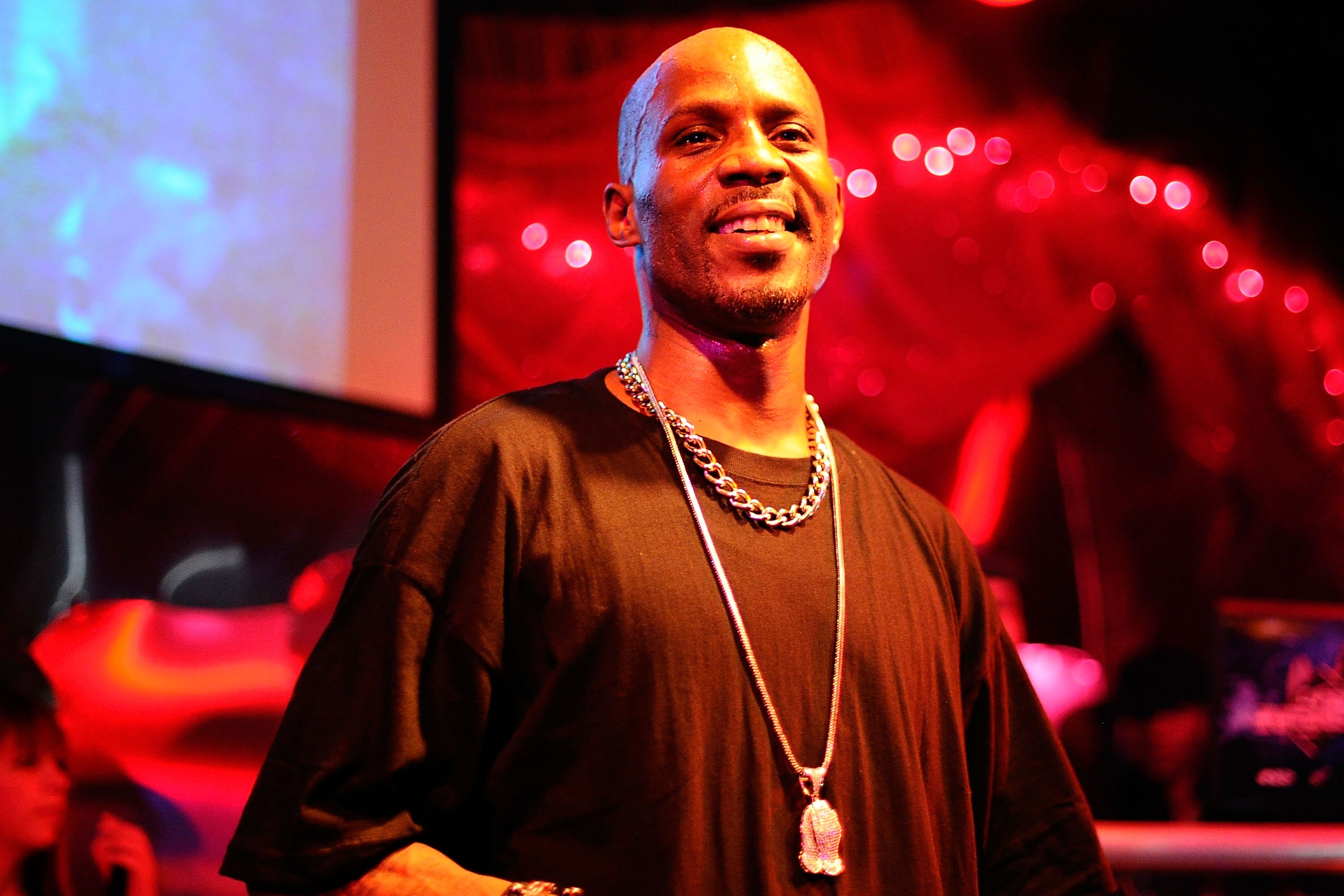 DMX smiling while wearing a black shirt and a chain at a concert.