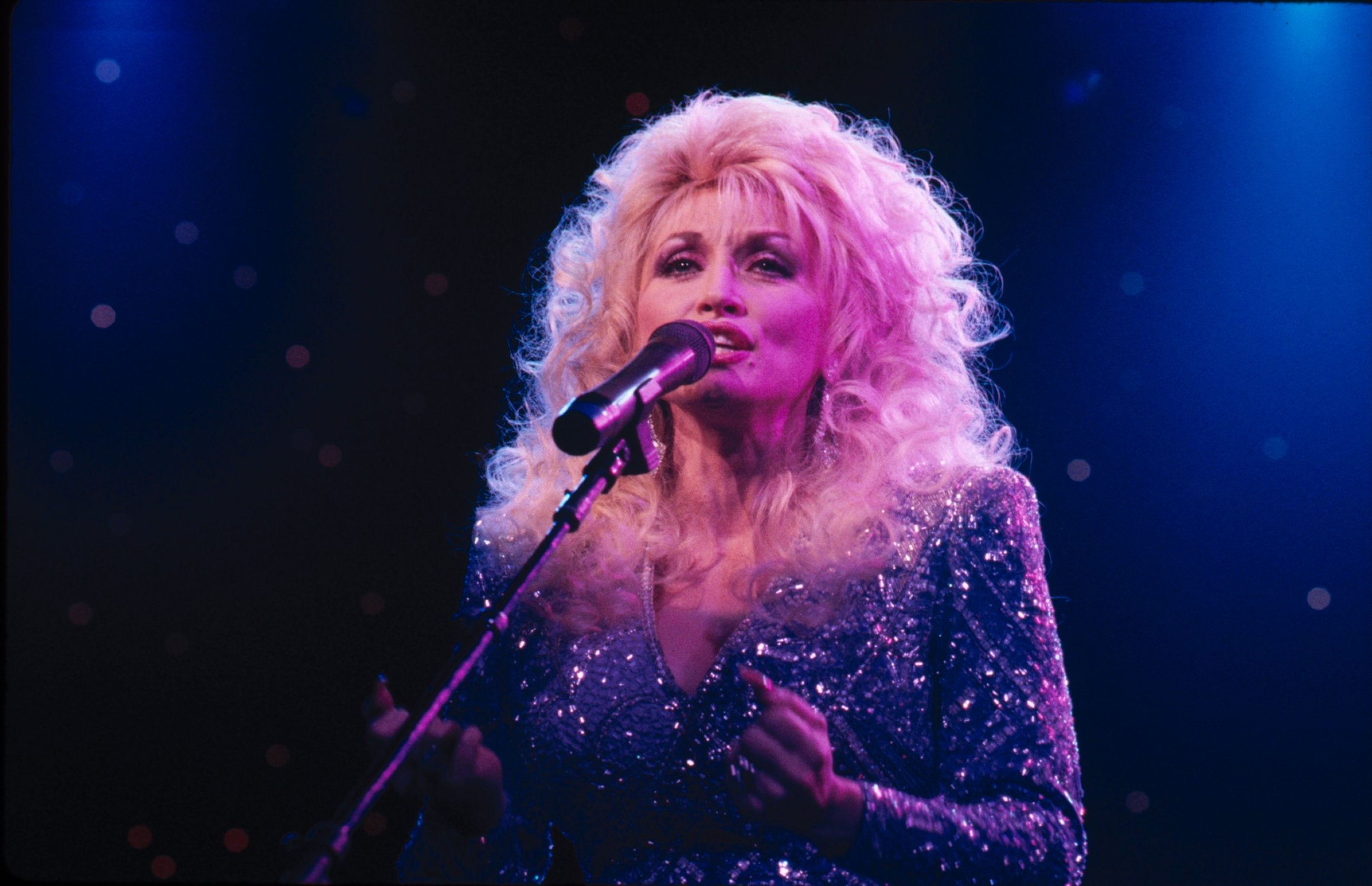 Dolly Parton singing into a microphone on stage.