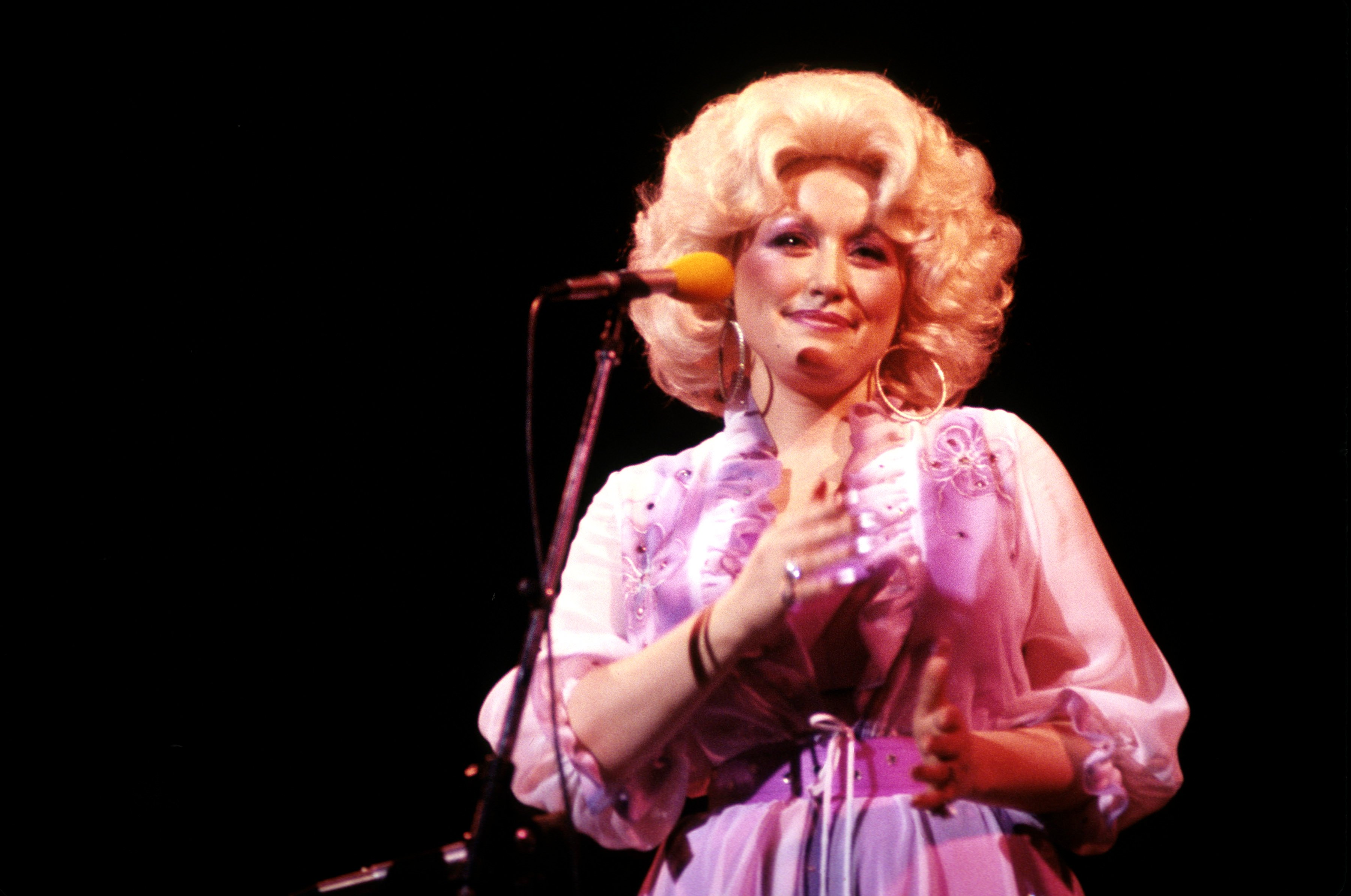 Dolly Parton on stage in a purple dress.