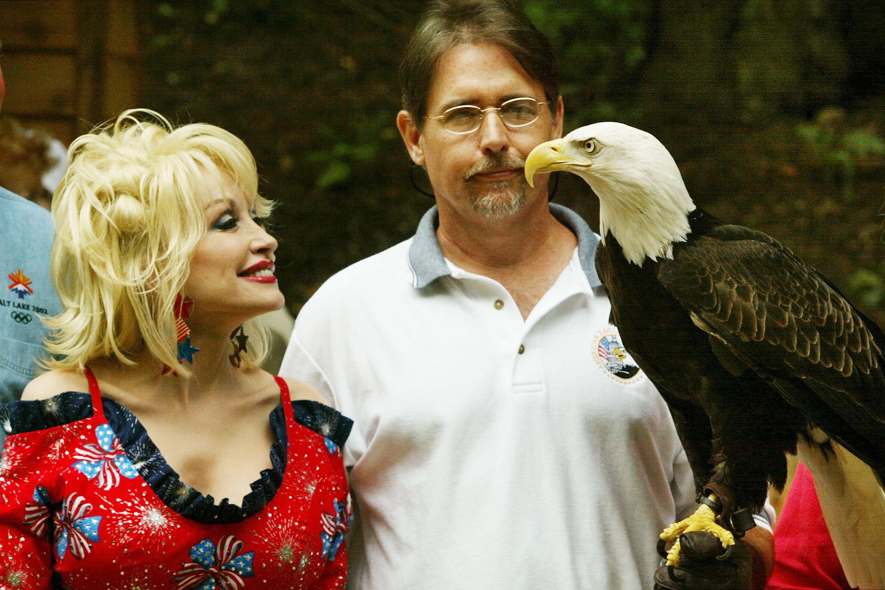 Dolly Parton stands next to a Bald Eagle named "America" being held by Al Cecere during an event at the National Zoo July 2, 2003 in Washington, DC.