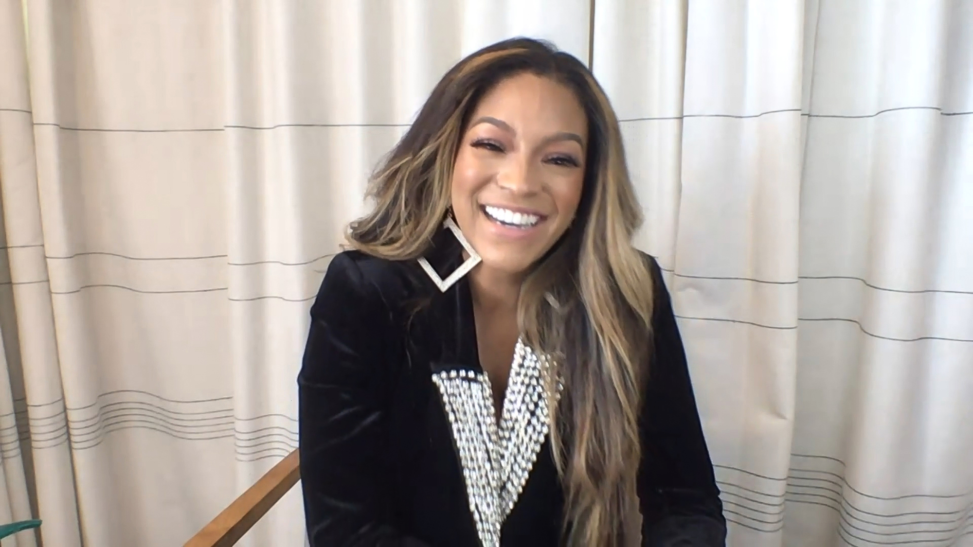 Drew Sidora laughing in front of a white curtain