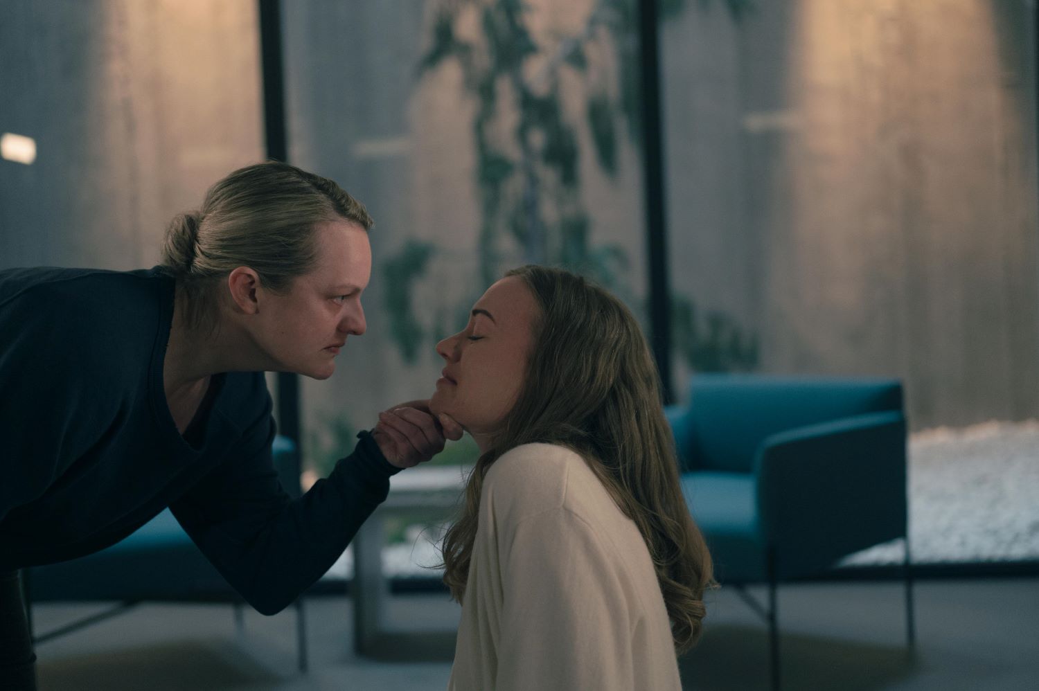 Elisabeth Moss as June confronts Yvonne Strahovski as Serena, holding her chin and staring her in the face, in a scene from 'The Handmaid's Tale'
