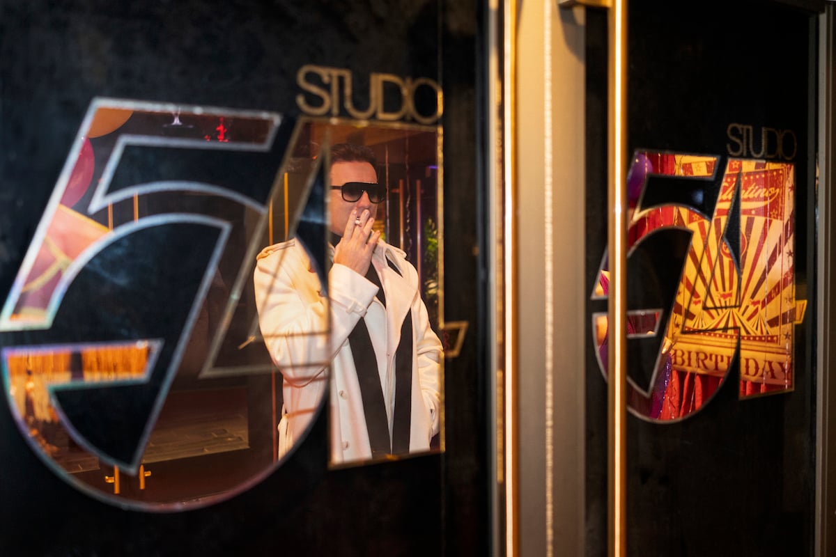 Ewan McGregor as Halston looking at windows of Studio 54