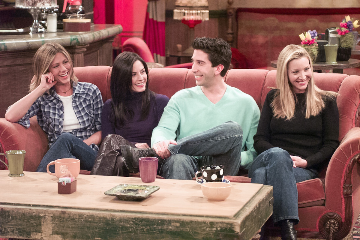 Jennifer Aniston, Courteney Cox, David Schwimmer, Lisa Kudrow sit on a couch as their character at Central Perk on 'Friends'