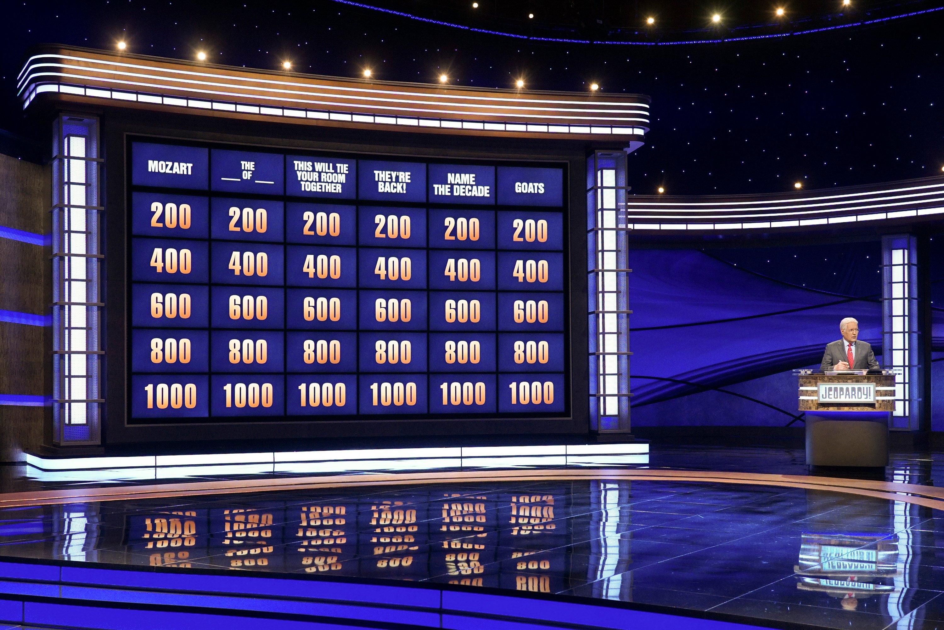 Late 'Jeopardy!' host Alex Trebek stands alongside the quiz show's clue board