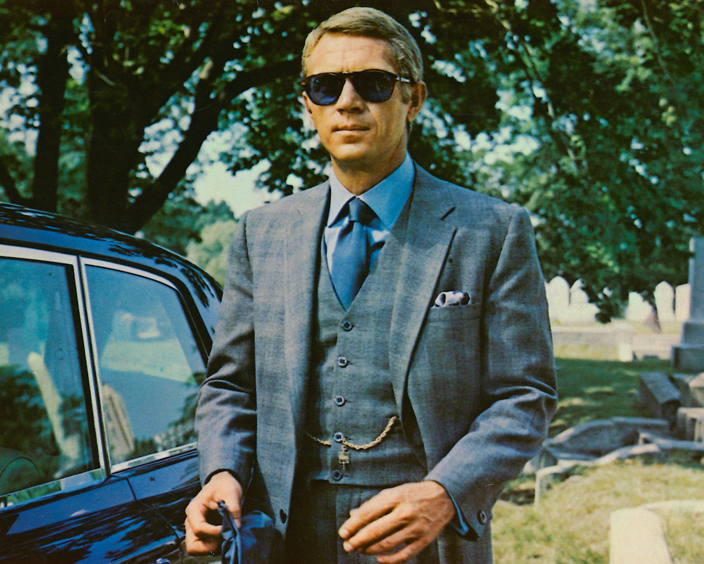 Steve McQueen wears sunglasses with a grey suit, a blue shirt and dark blue tie in a publicity image issued for the film, 'The Thomas Crown Affair,' 1968. 
