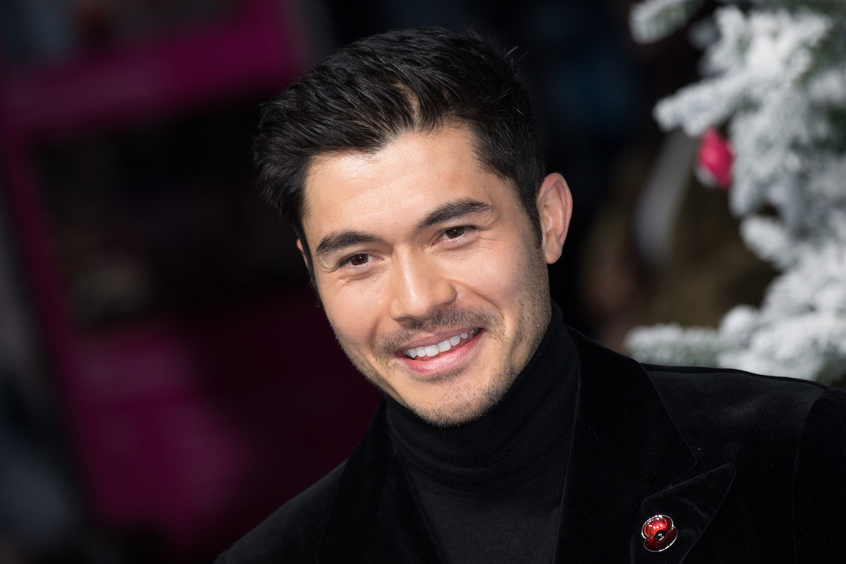 Henry Golding wears black and smiles at the UK premiere for ‘Last Christmas’