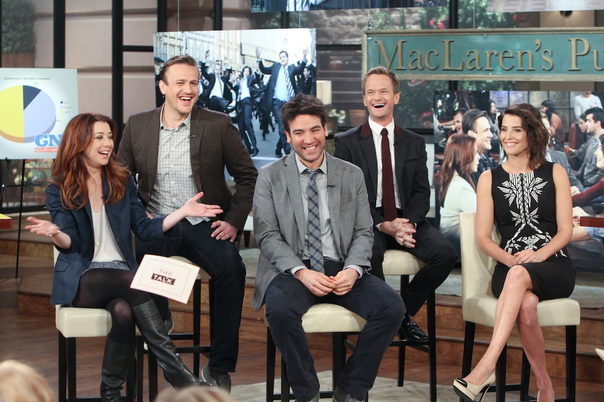 The cast of 'How I Met Your Mother' smile and laugh in front of images from the show on 'The Talk'