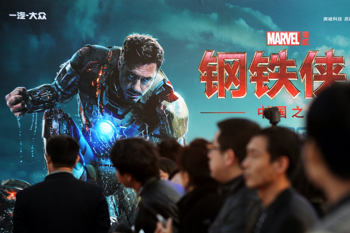 Attendees sit in front of a poster during a promotional event for 'Iron Man 3' in Beijing