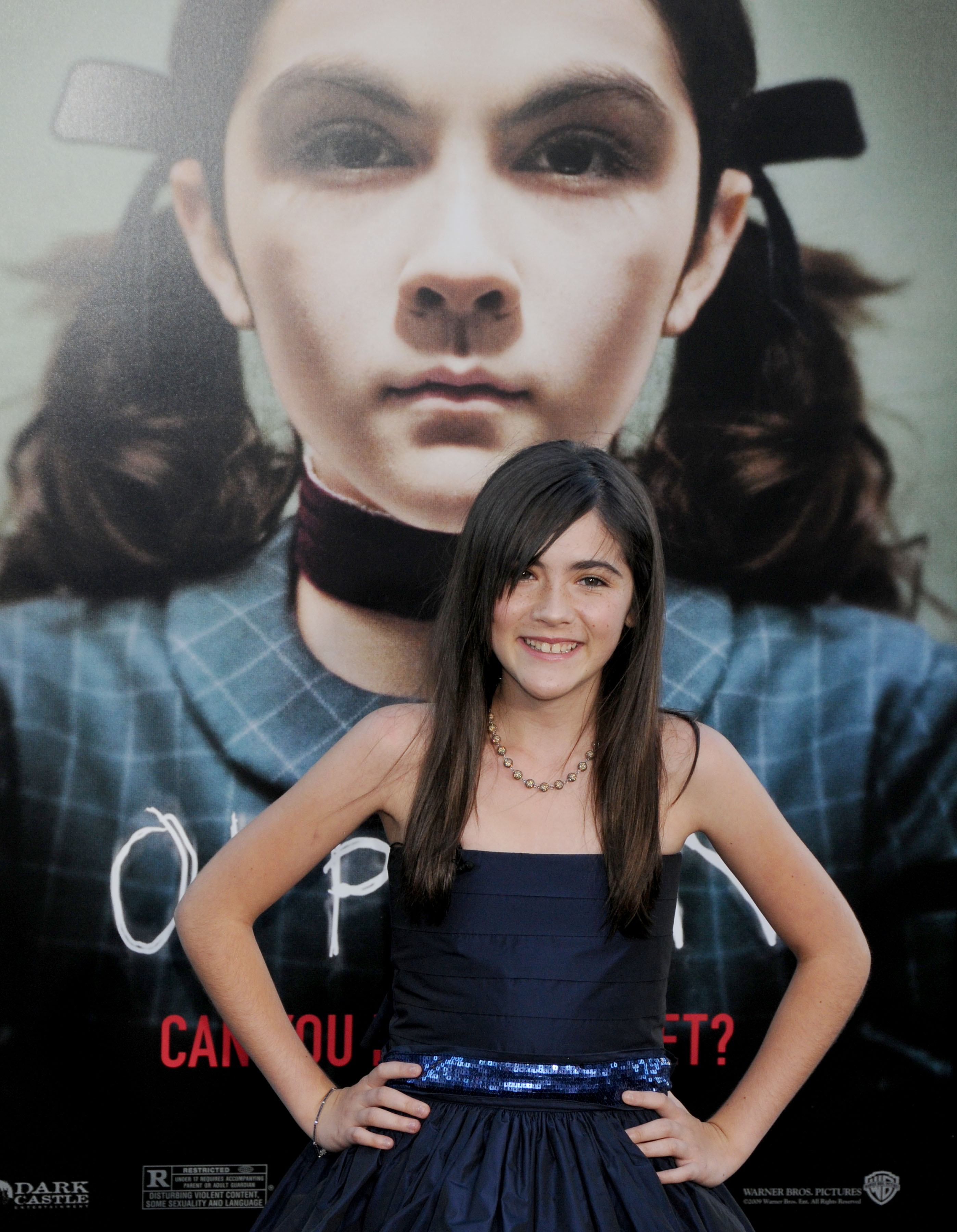 Isabelle Fuhrman stands in front of an Orphan poster