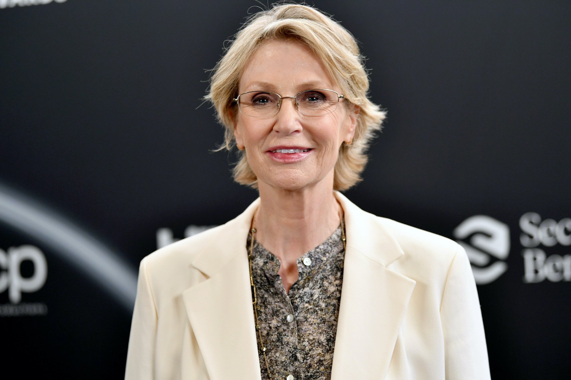 Jane Lynch smiling in front of a black background