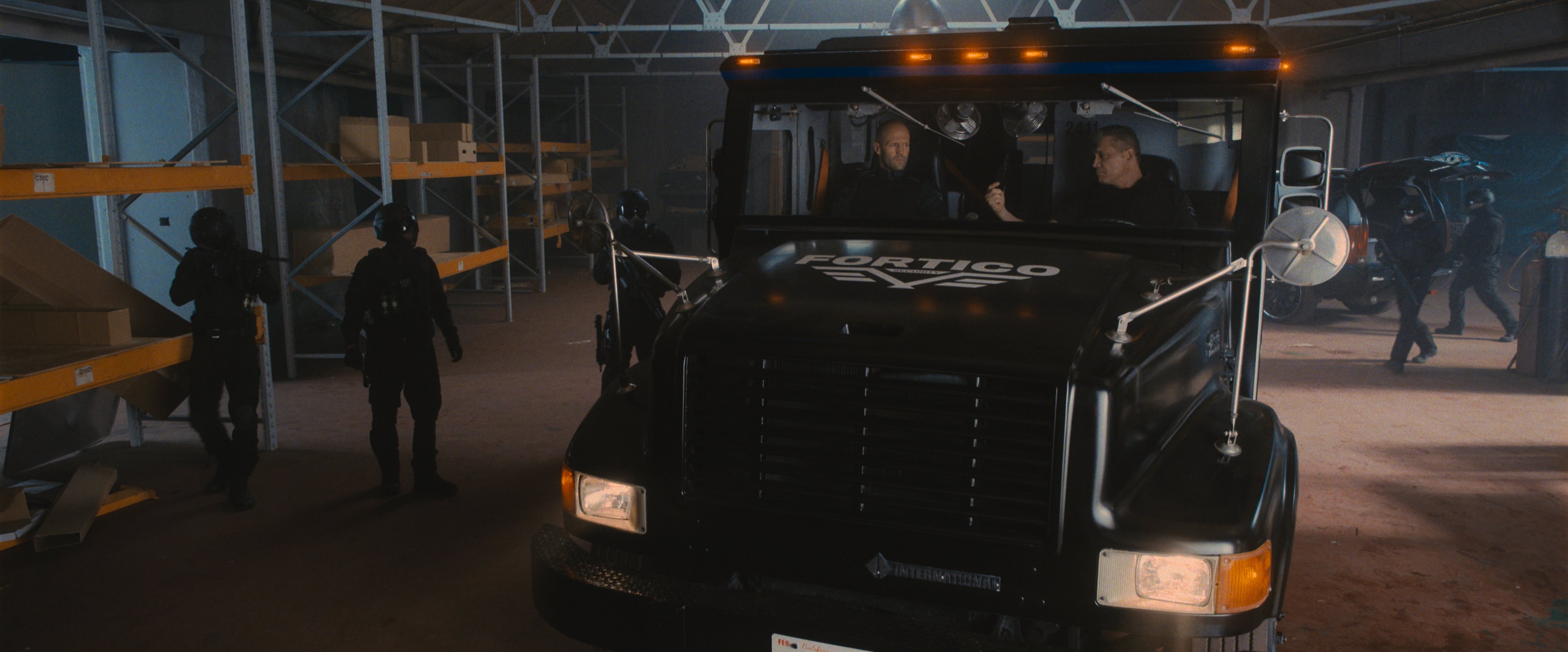Jason Statham and Holt McAllany drive the truck in Wrath of Man
