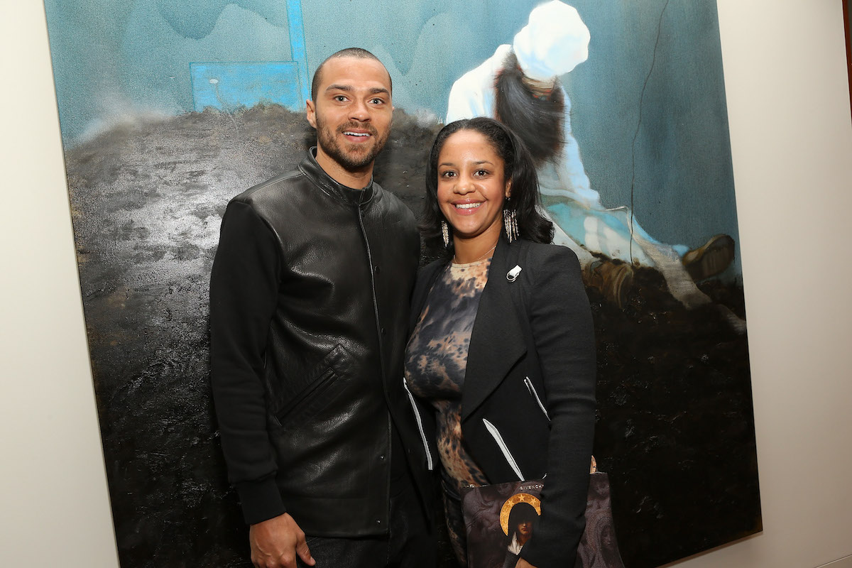 Jesse Williams and Aryn Drake-Lee pose together smiling in front of a painting