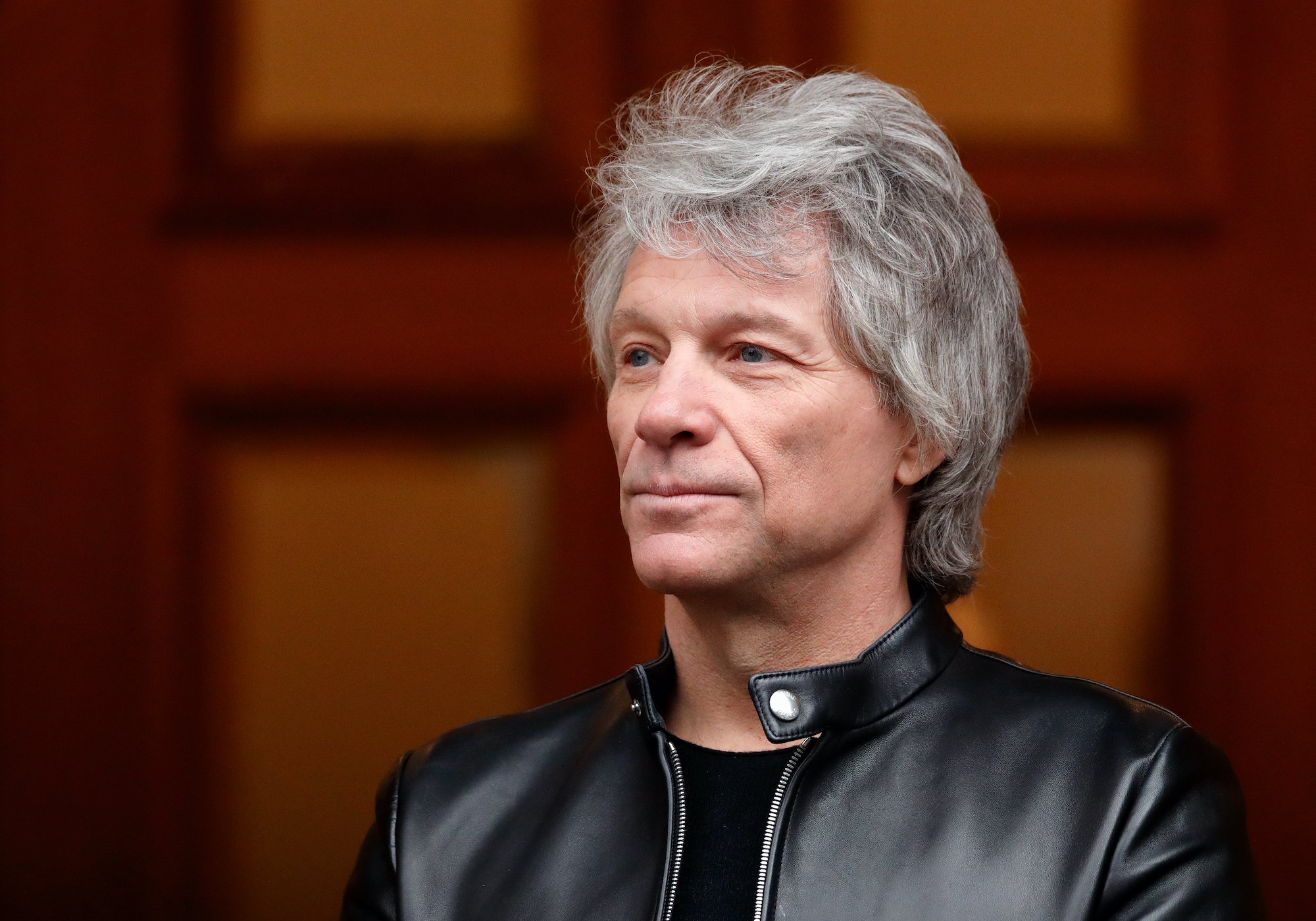 Jon Bon Jovi smiling in front of a wooden door