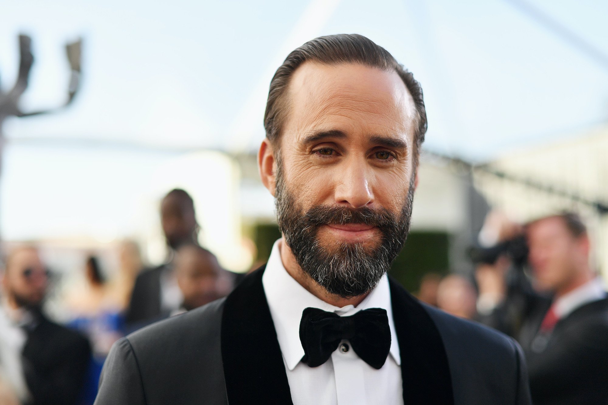 Joseph Fiennes smiling in front of a blurred crowd