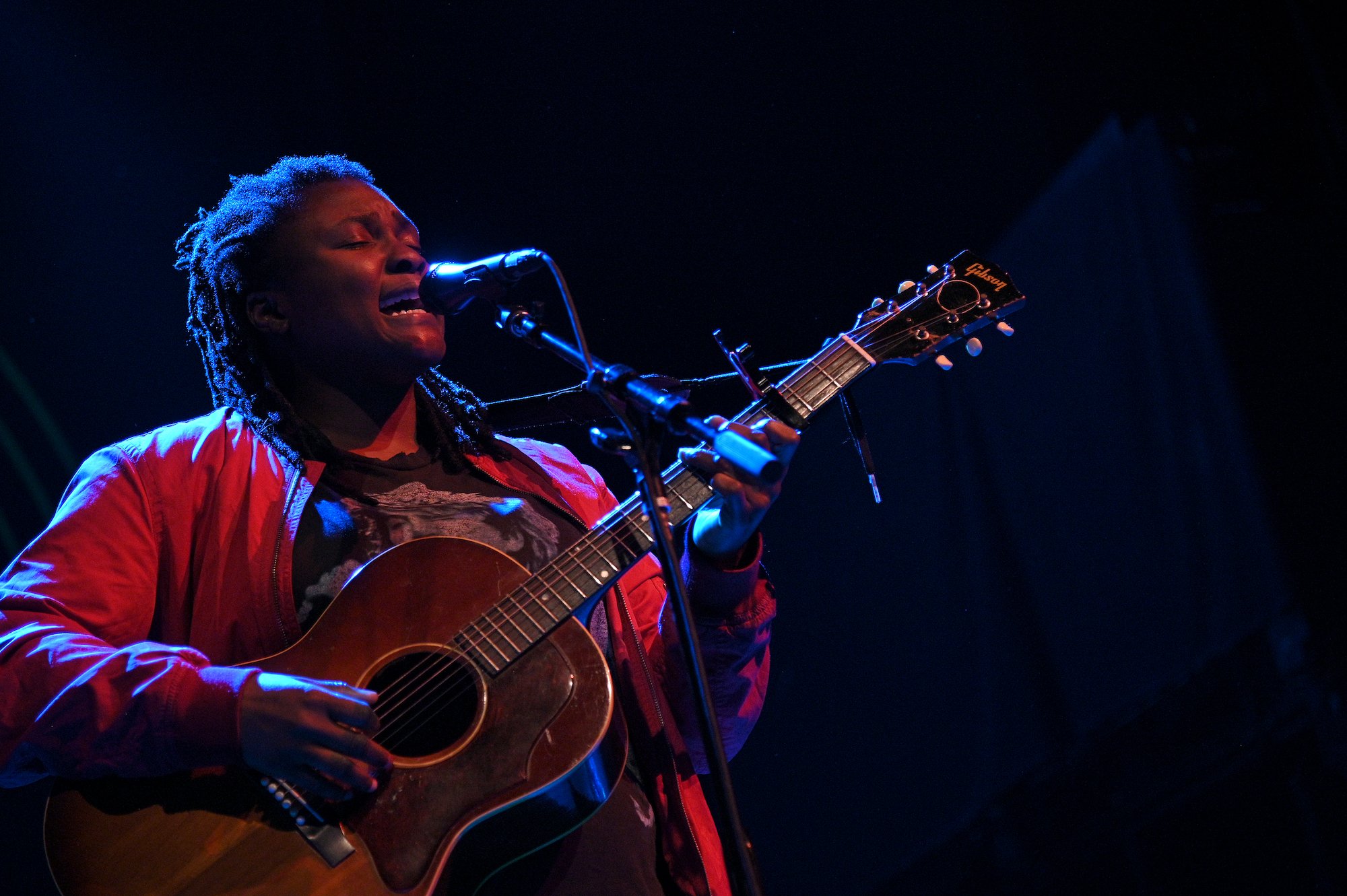 Joy Oladokun singing, playing a guitar