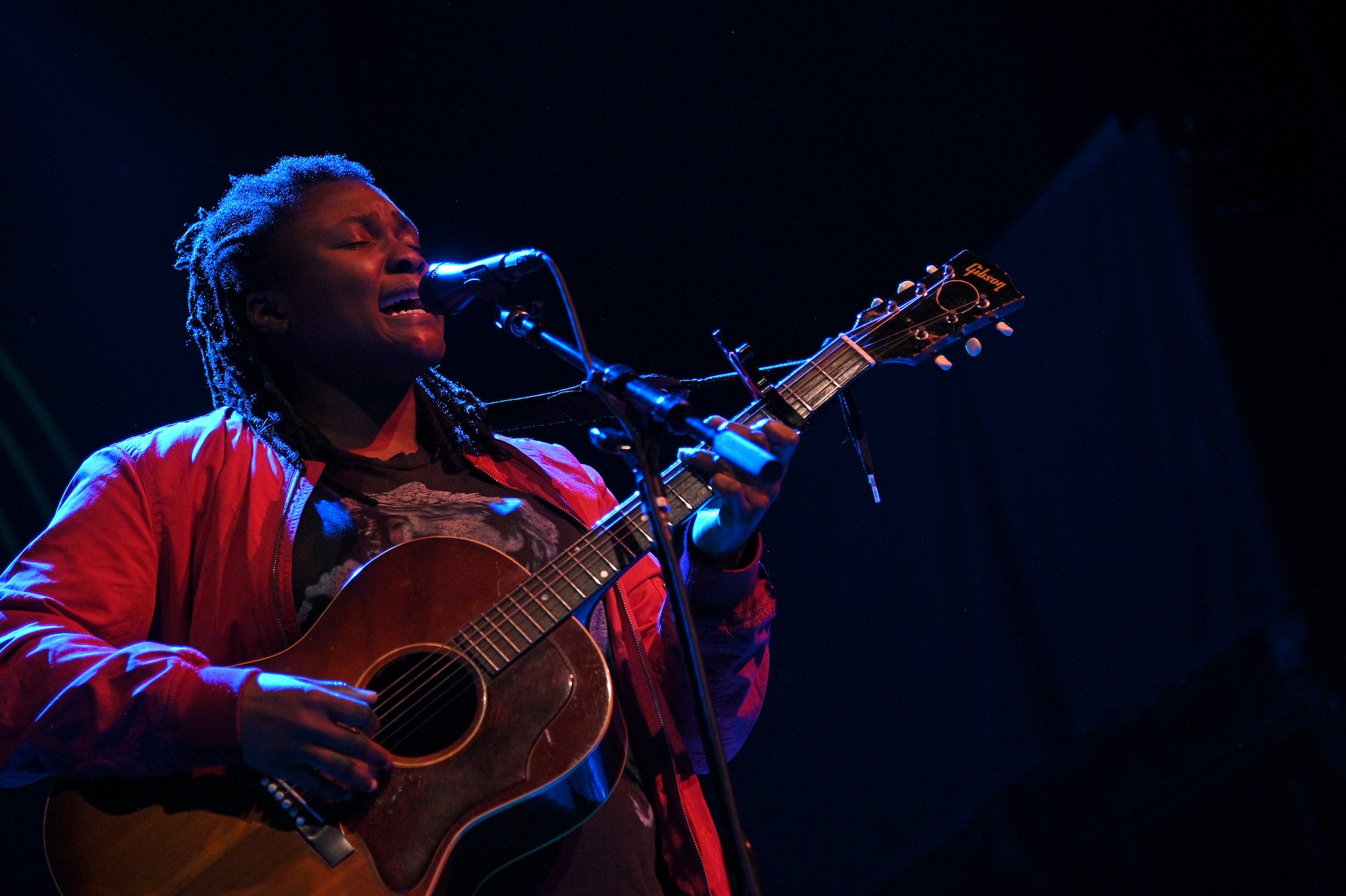 Joy Oladokun singing, playing a guitar